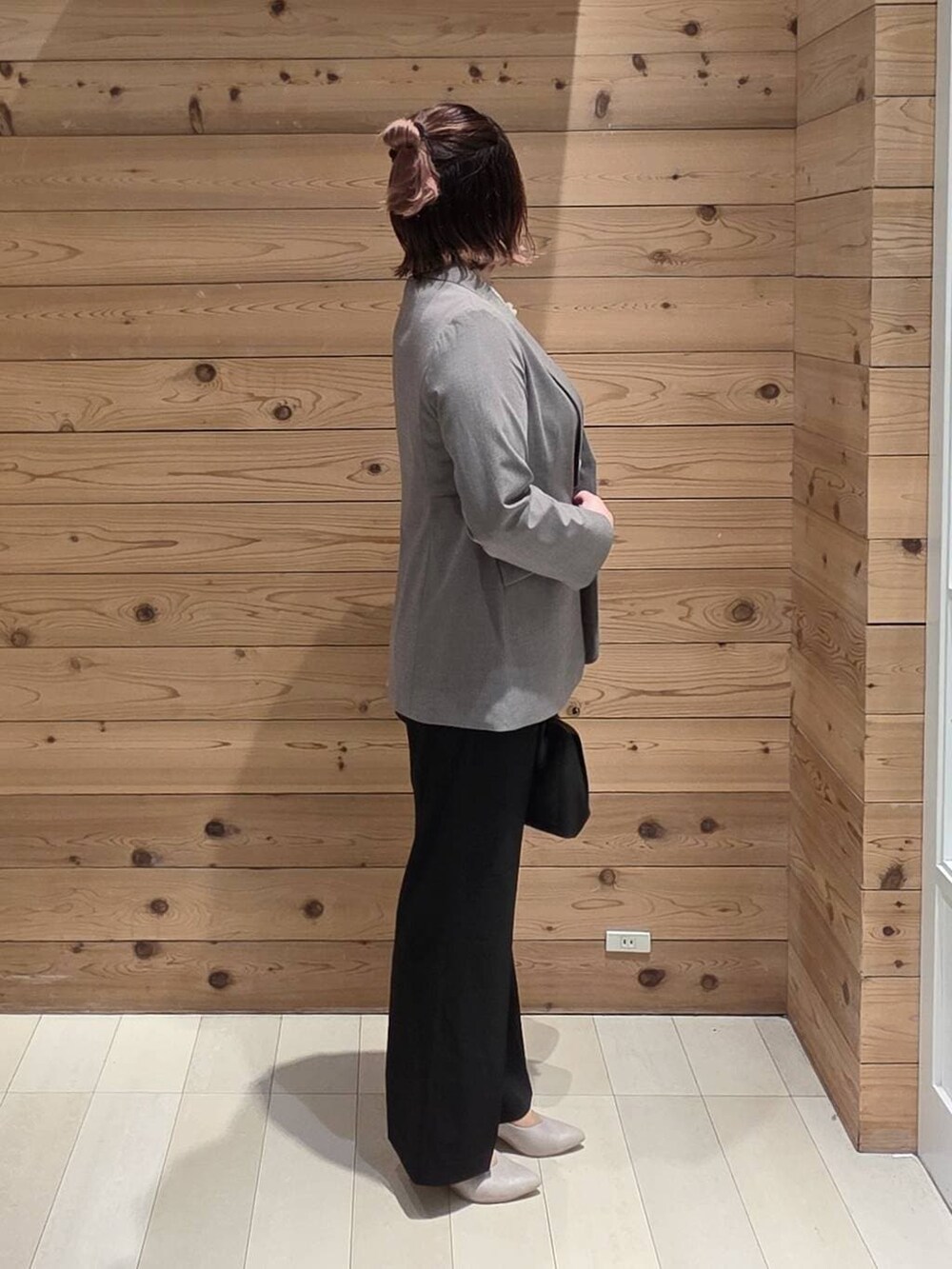 ブラック系のショルダーバッグ、ホワイト系のパンプス、ブラック系のスラックスを着用したレディースの冬コーディネートの2枚目の写真