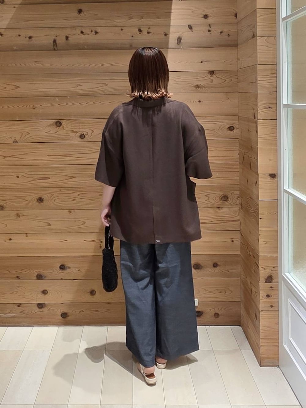 ブラウン系のテーラードジャケット、ブルー系のその他パンツ、ブラック系のクラッチバッグを着用したレディースの夏コーディネートの3枚目の写真
