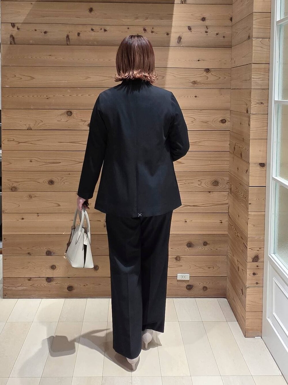 ホワイト系のショルダーバッグ、ホワイト系のパンプス、ブルー系のスラックスを着用したレディースの冬コーディネートの3枚目の写真