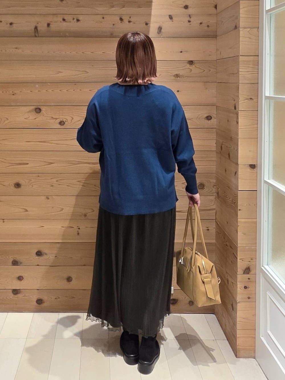 ブラック系のボストンバッグ、ブラック系のダウンジャケット/コート、ブルー系のニット/セーターを着用したレディースの秋コーディネートの3枚目の写真