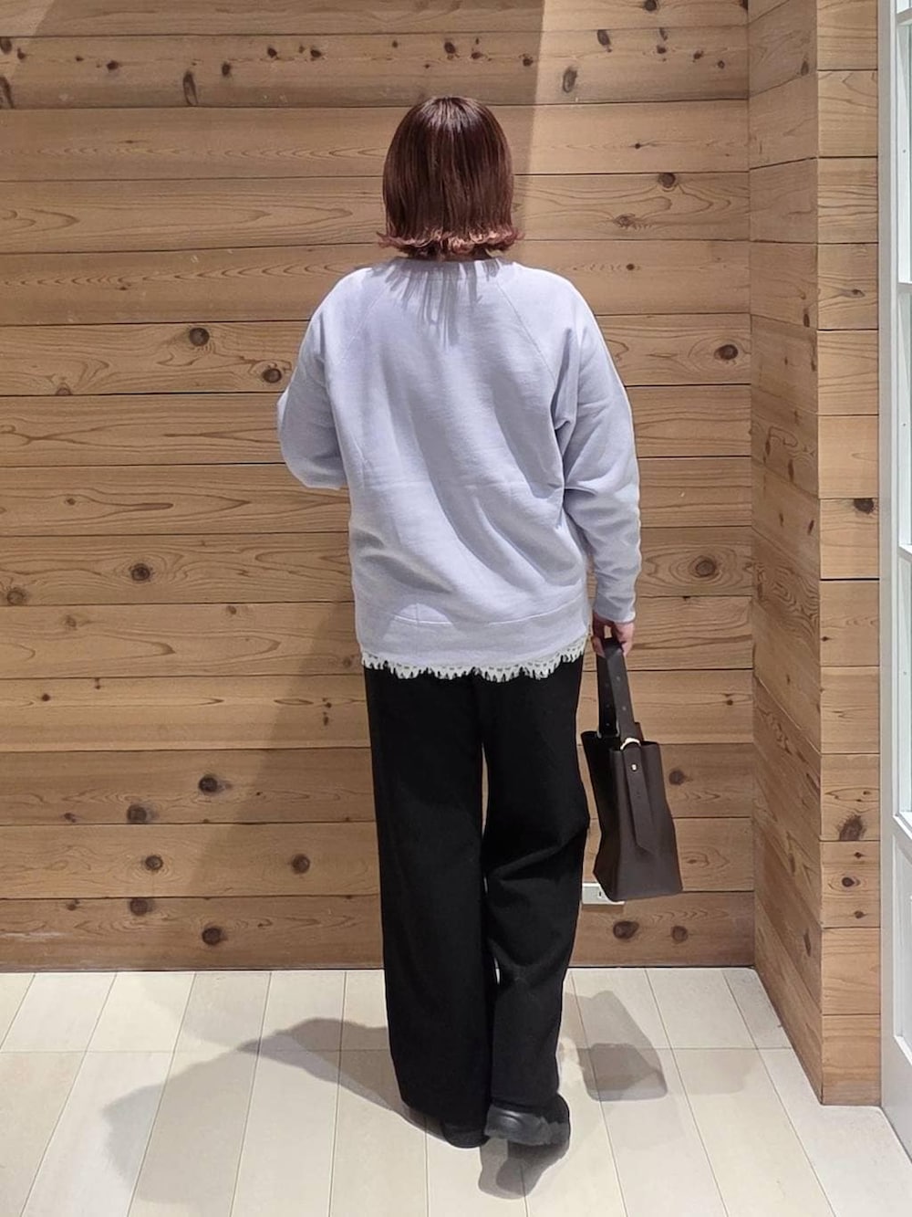 ブラウン系のショルダーバッグ、ブルー系のダウンジャケット/コート、ブラック系のブーツを着用したレディースの冬コーディネートの3枚目の写真