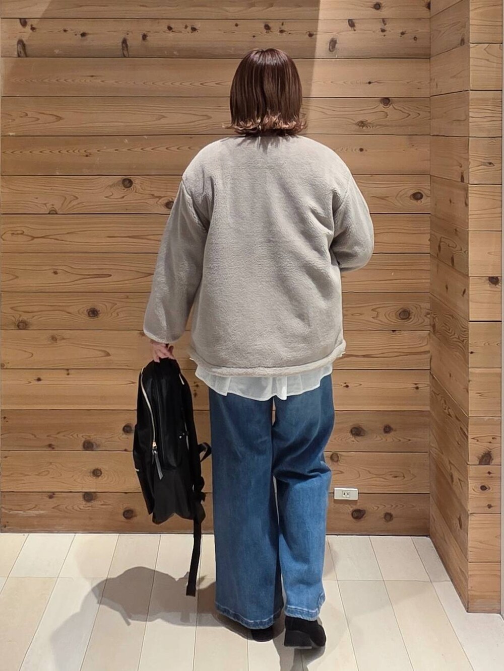 ブラウン系のブルゾン、ブラック系のバックパック/リュック、ホワイト系のTシャツ/カットソーを着用したレディースの冬コーディネートの3枚目の写真