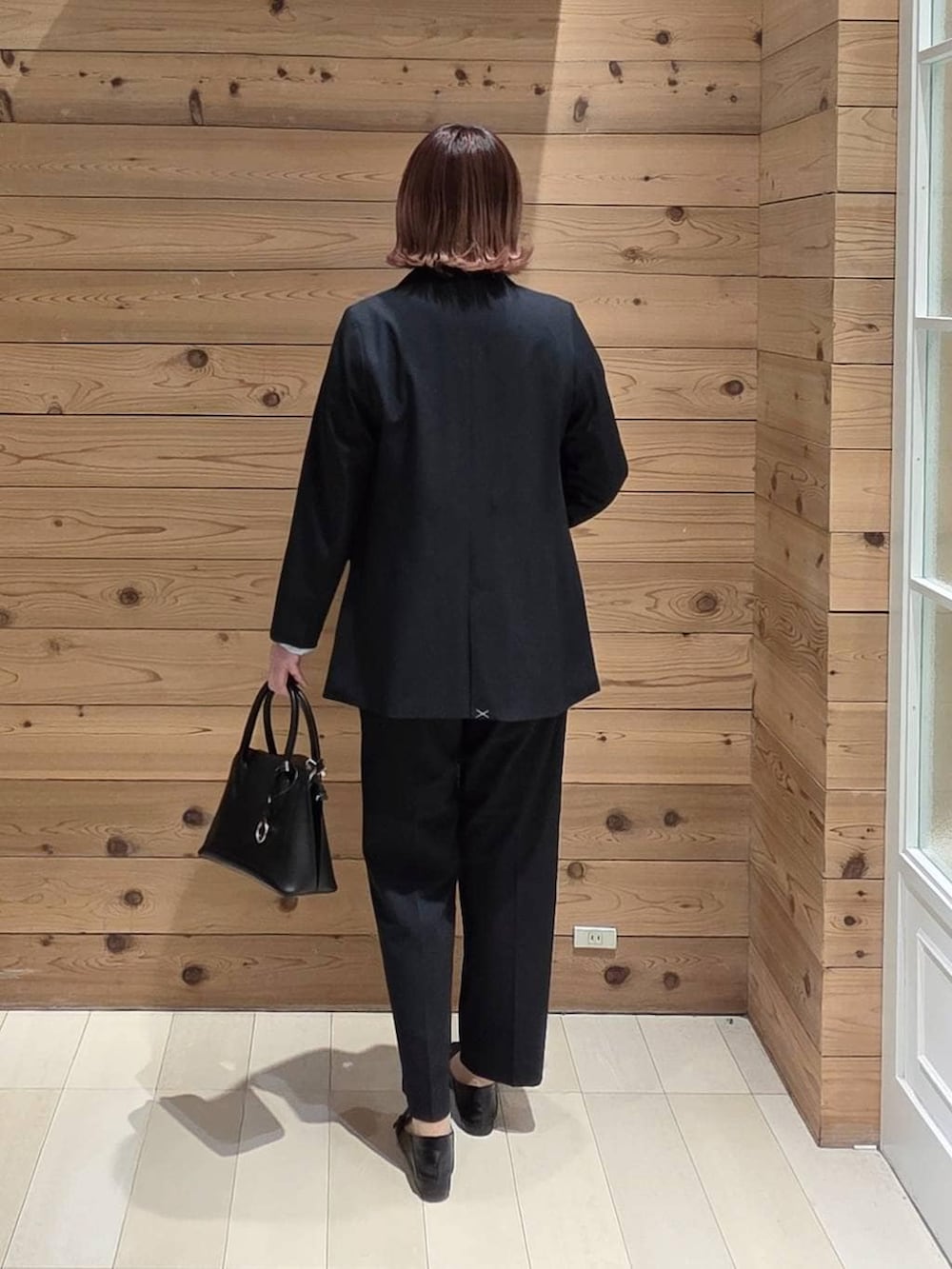 ブラック系のローファー、ブラック系のショルダーバッグ、ブラック系のスラックスを着用したレディースの春コーディネートの3枚目の写真