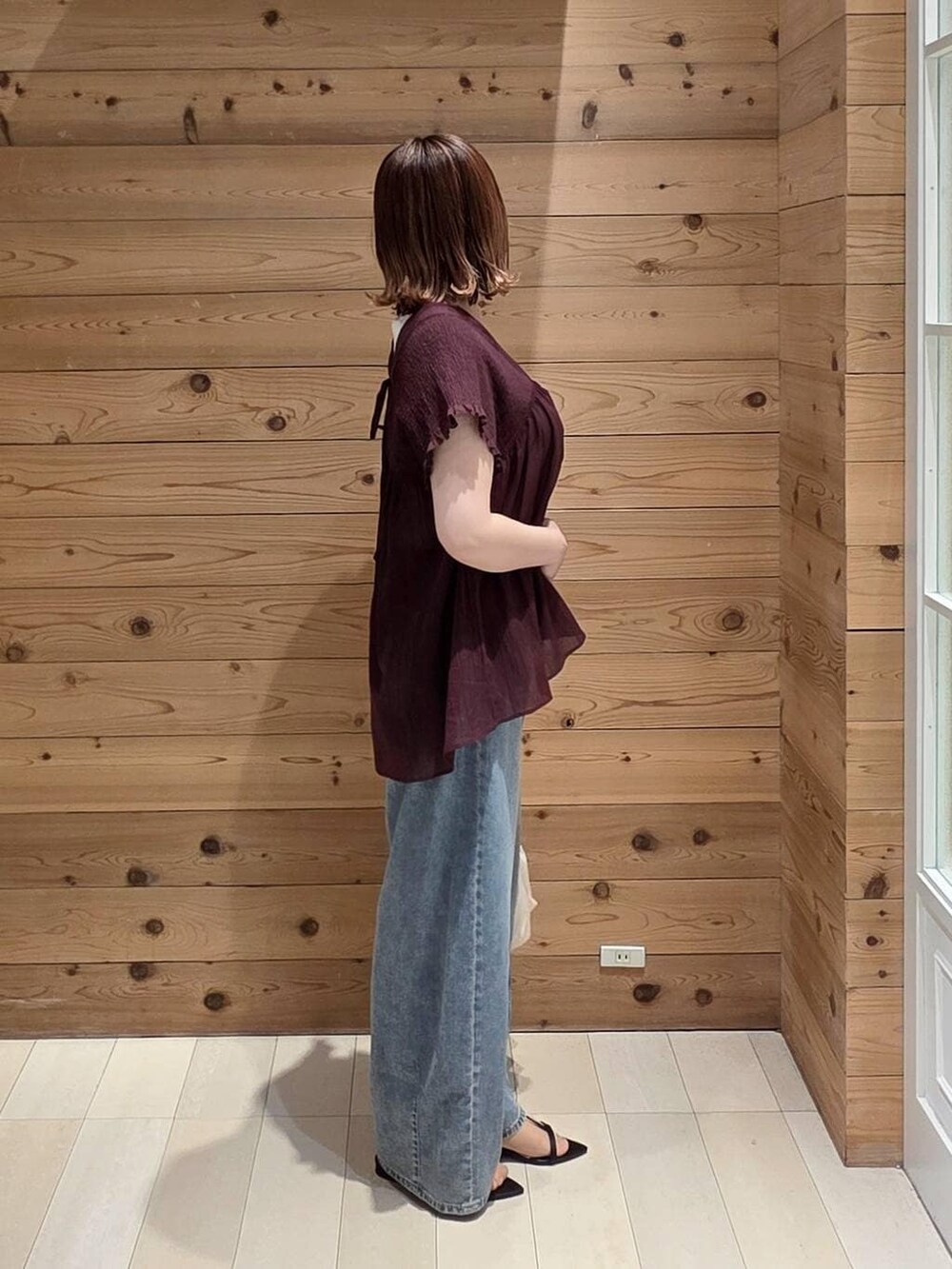 ホワイト系のショルダーバッグ、ブルー系のデニムパンツ、ホワイト系のタンクトップを着用したレディースの夏コーディネートの3枚目の写真