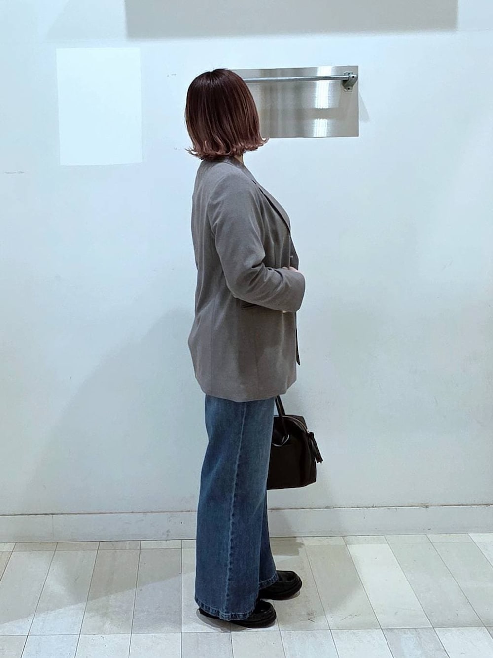 ブラック系のローファー、ブラウン系のボストンバッグ、ブルー系のデニムパンツを着用したレディースの春コーディネートの2枚目の写真