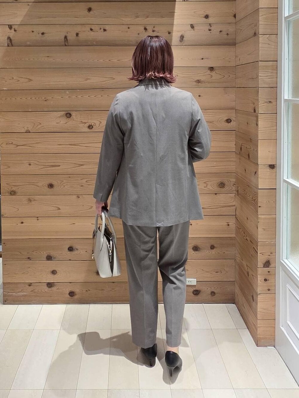 ホワイト系のショルダーバッグ、ブラック系のパンプス、ブラウン系のスラックスを着用したレディースの冬コーディネートの3枚目の写真