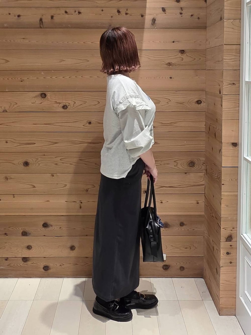 ブラック系のローファー、ブラック系のボストンバッグ、グレー系のスカートを着用したレディースの秋コーディネートの2枚目の写真