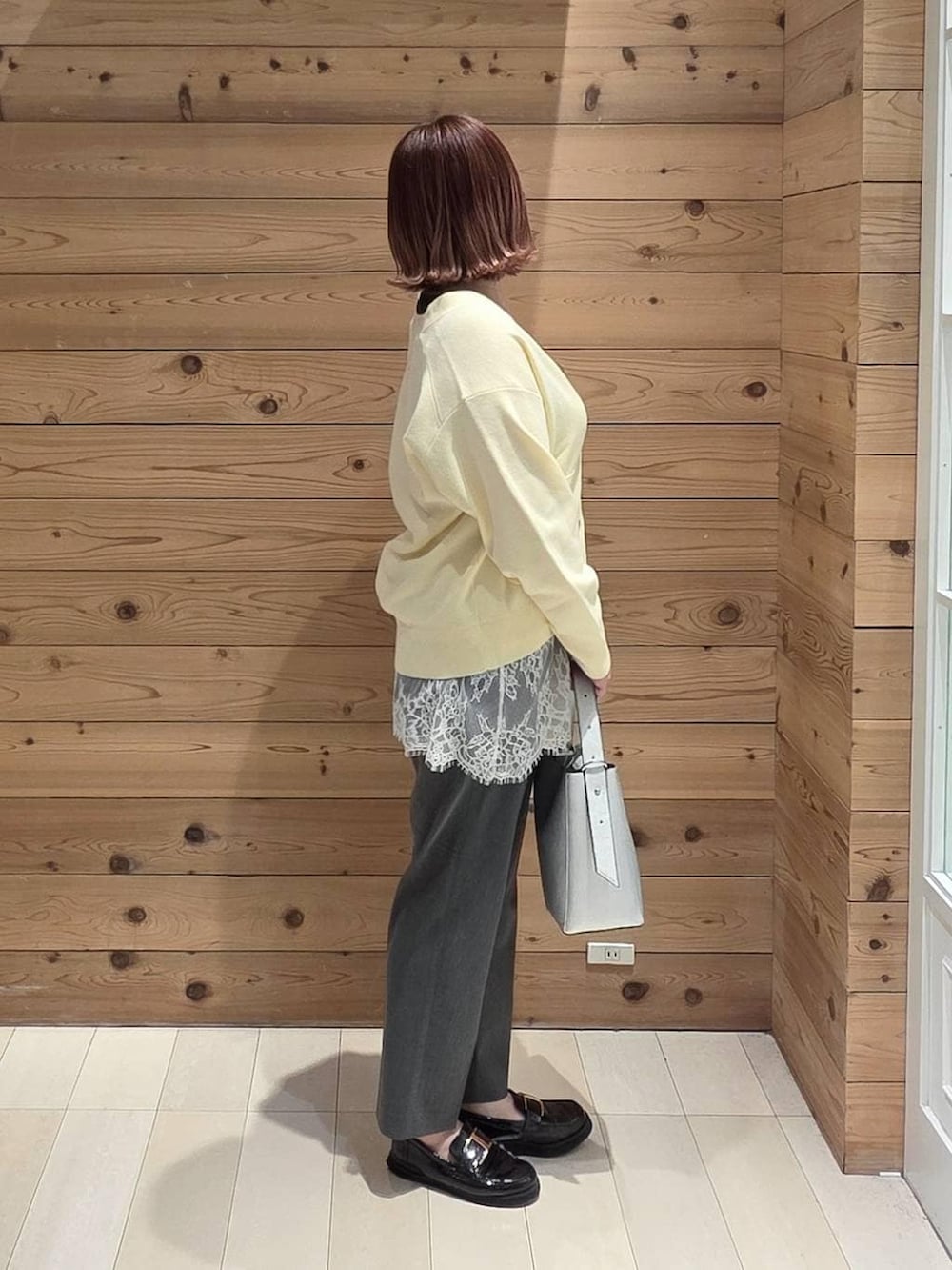 ブラック系のローファー、シルバー系のショルダーバッグ、グレー系のスラックスを着用したレディースの春コーディネートの2枚目の写真