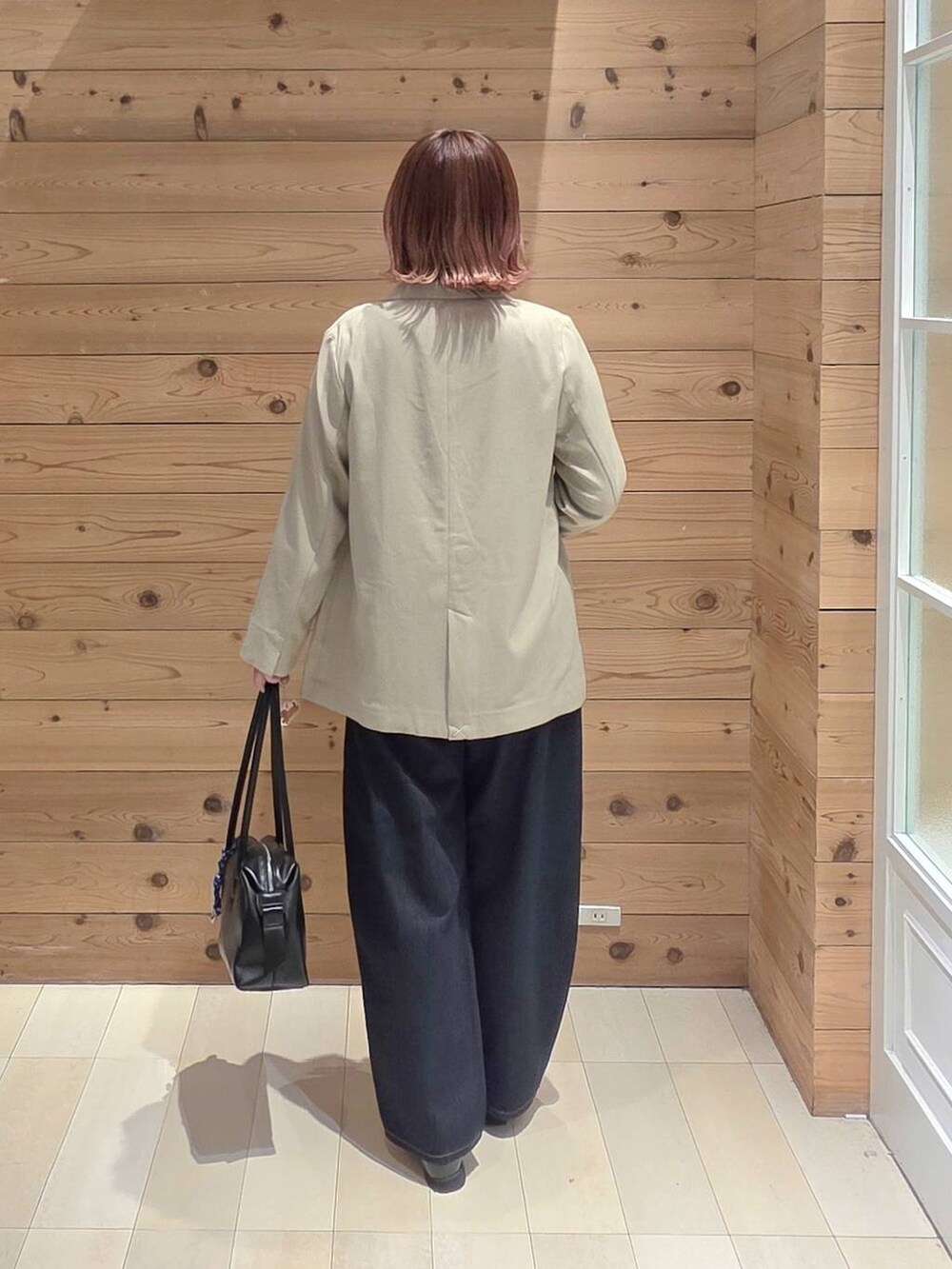 ブラック系のローファー、ブラック系のボストンバッグ、ブルー系のデニムパンツを着用したレディースの春コーディネートの3枚目の写真
