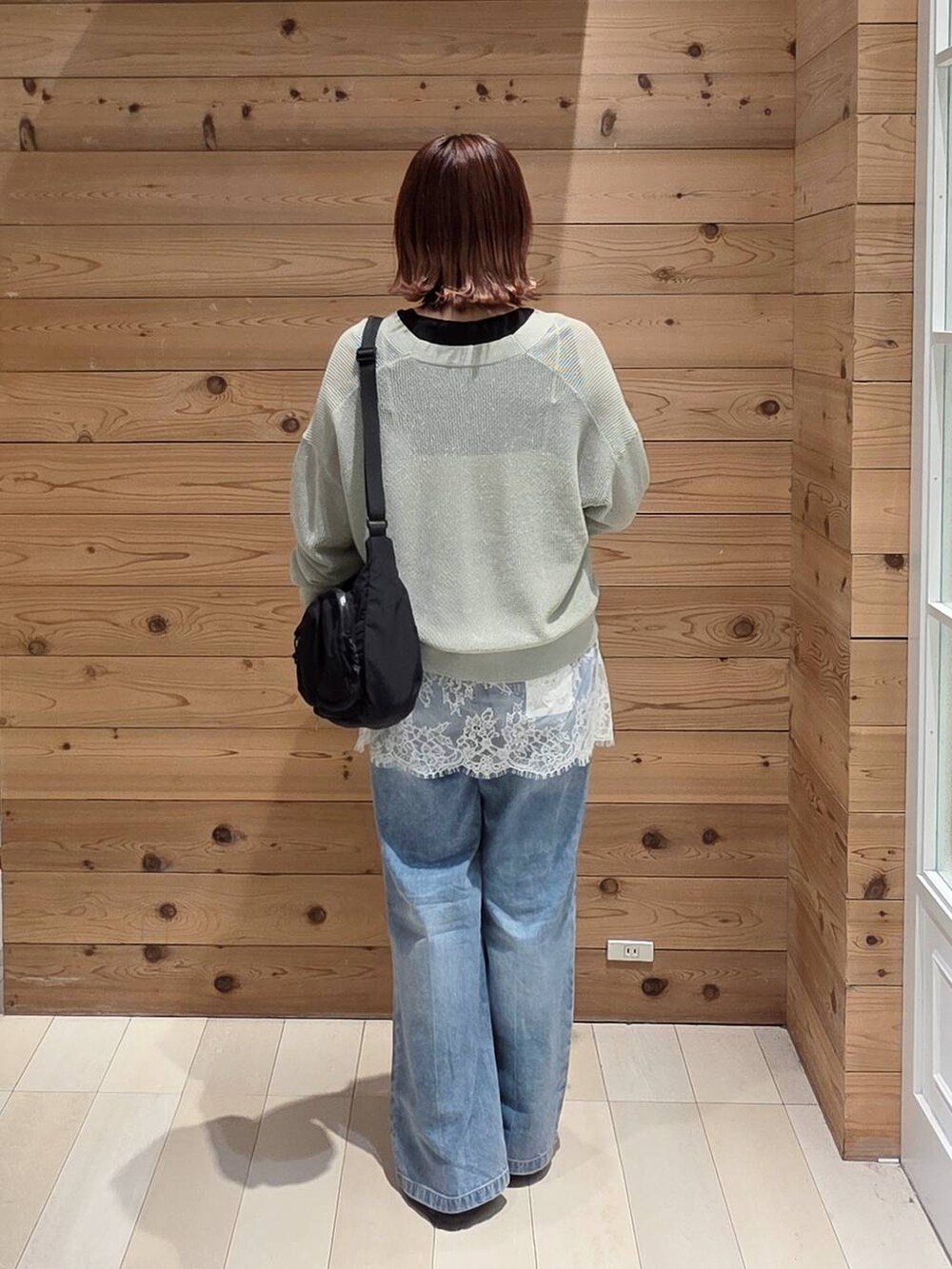 ブルー系のデニムパンツ、ブラック系のタンクトップ、グリーン系のカーディガン/ボレロを着用したレディースの春コーディネートの3枚目の写真