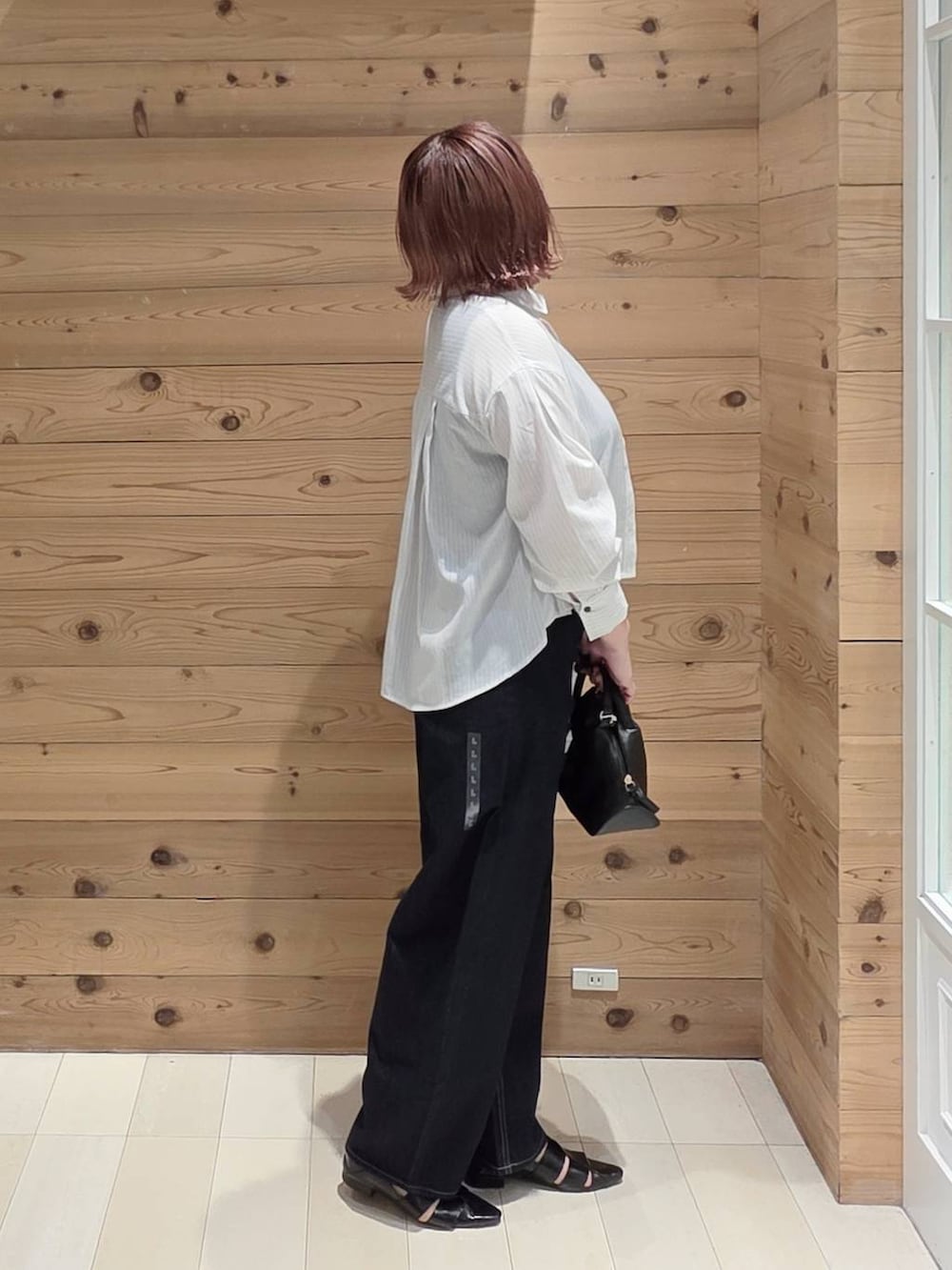 ブラック系のショルダーバッグ、ブルー系のデニムパンツ、ブラック系のタンクトップを着用したレディースの夏コーディネートの2枚目の写真