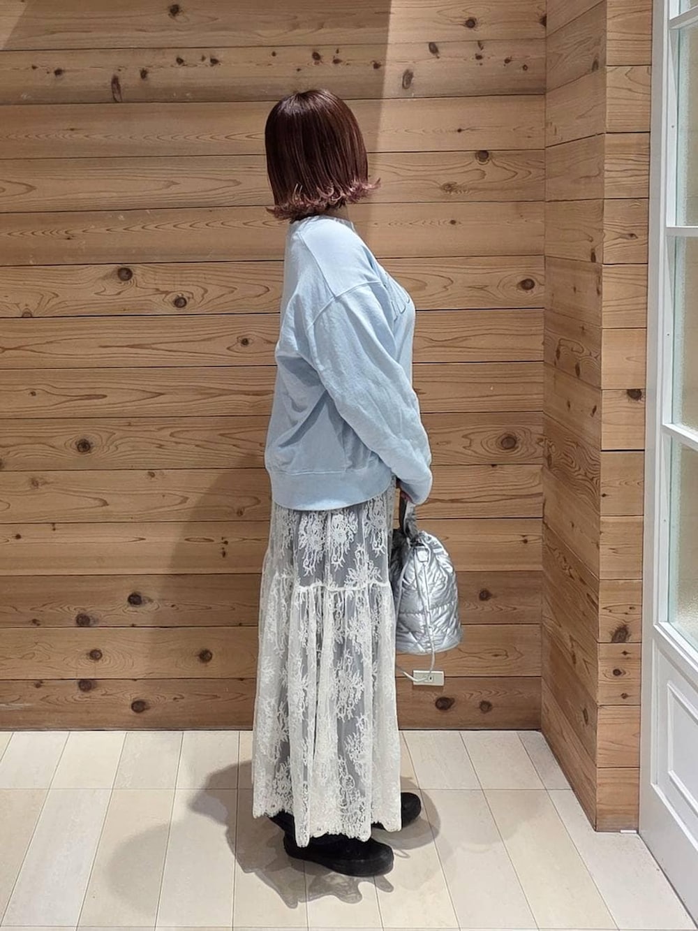 ブルー系のデニムパンツ、シルバー系のハンドバッグ、ブラウン系のワンピースを着用したレディースの春コーディネートの2枚目の写真