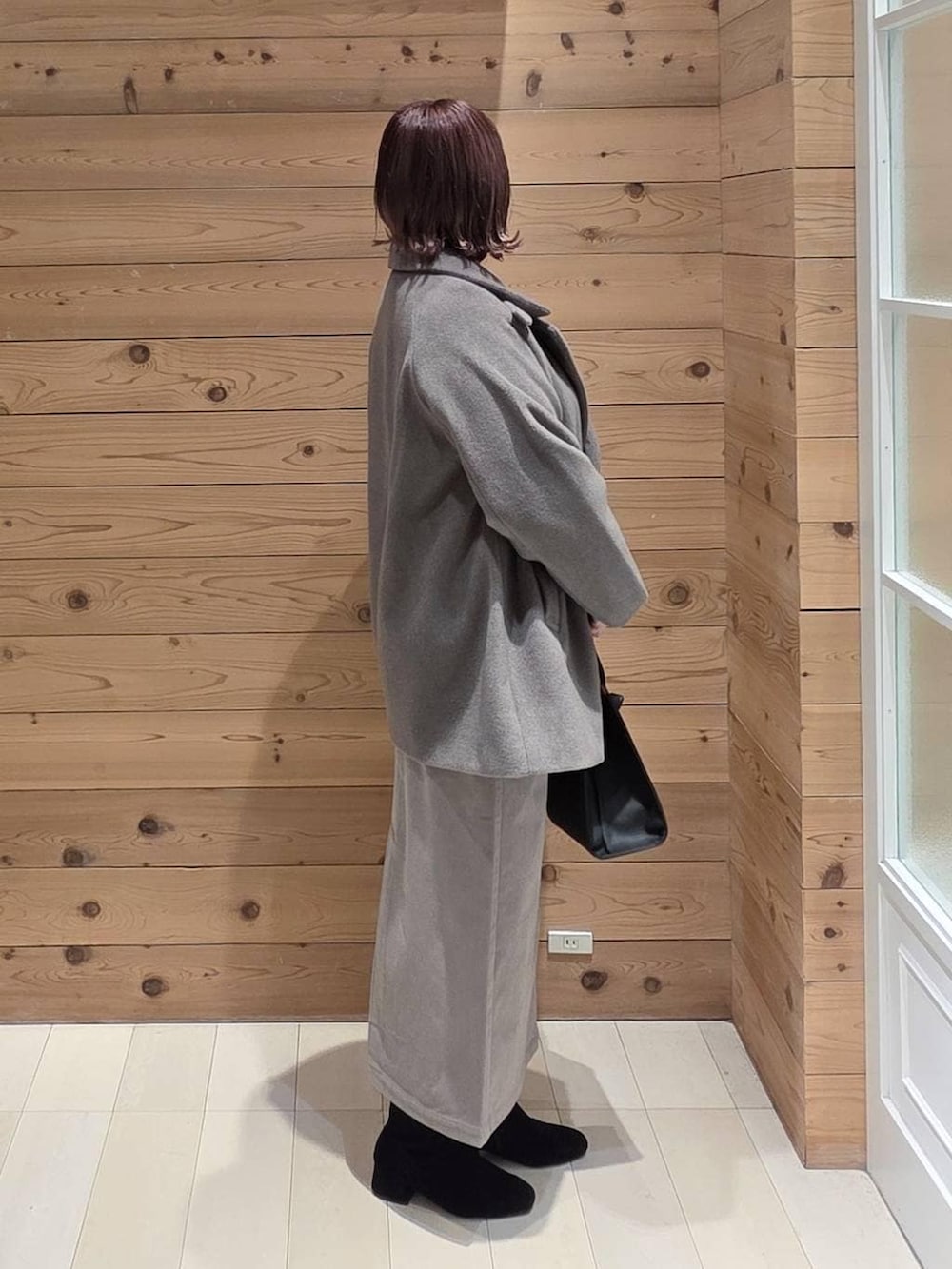 ブラック系のショルダーバッグ、ブラウン系のチェスターコート、ブラウン系のスカートを着用したレディースの冬コーディネートの2枚目の写真