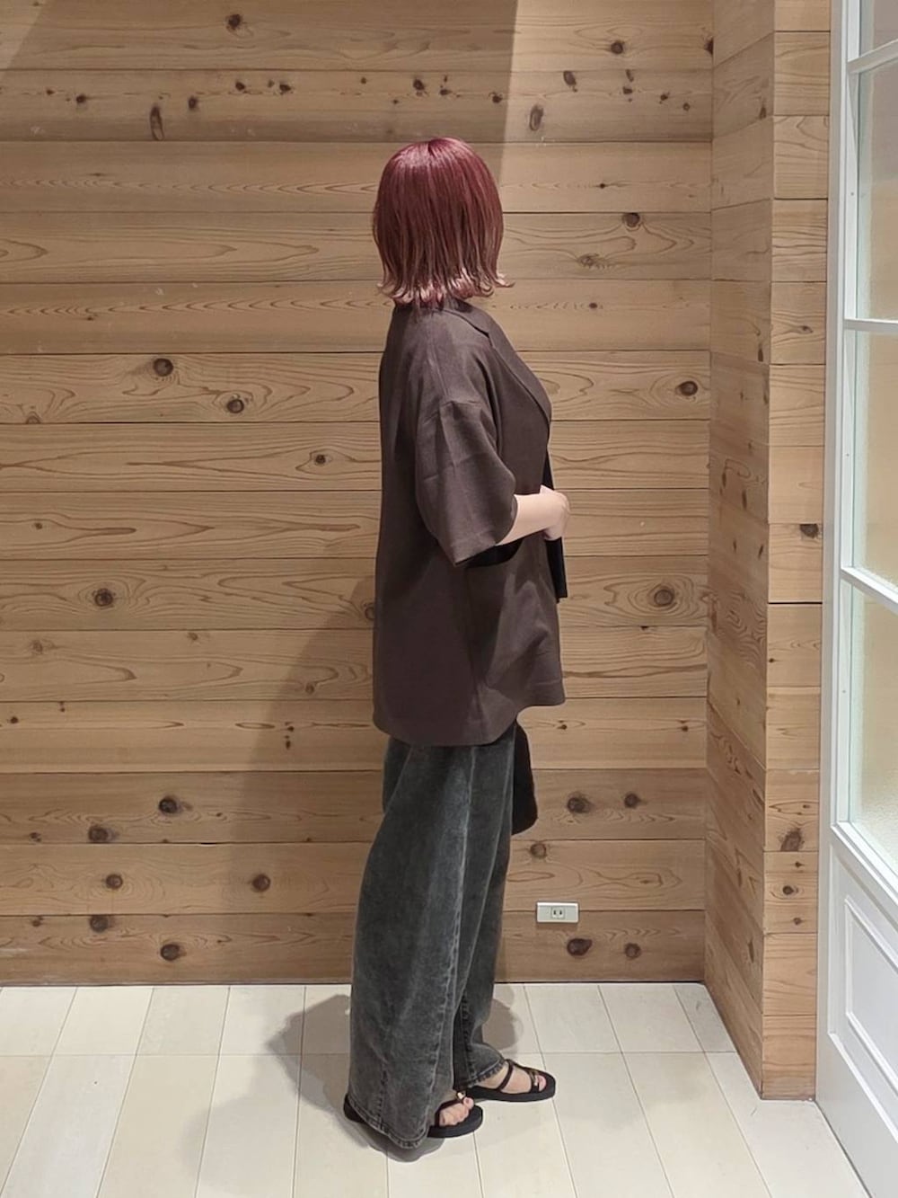 ブラック系のハンドバッグ、ブラック系のデニムパンツ、ブラウン系のテーラードジャケットを着用したレディースの夏コーディネートの2枚目の写真