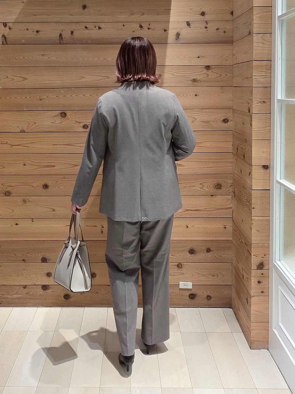 ホワイト系のショルダーバッグ、ブラック系のパンプス、ブラウン系のスラックスを着用したレディースの冬コーディネートの3枚目の写真