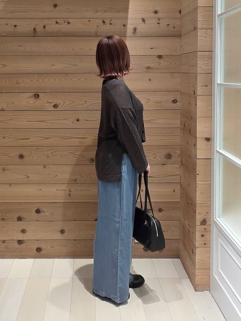 ブラック系のローファー、ブラック系のショルダーバッグ、ブルー系のデニムパンツを着用したレディースの春コーディネートの2枚目の写真