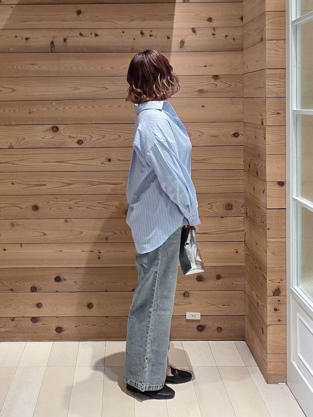 ブラック系のローファー、シルバー系のショルダーバッグ、ブルー系のデニムパンツを着用したレディースの春コーディネートの2枚目の写真