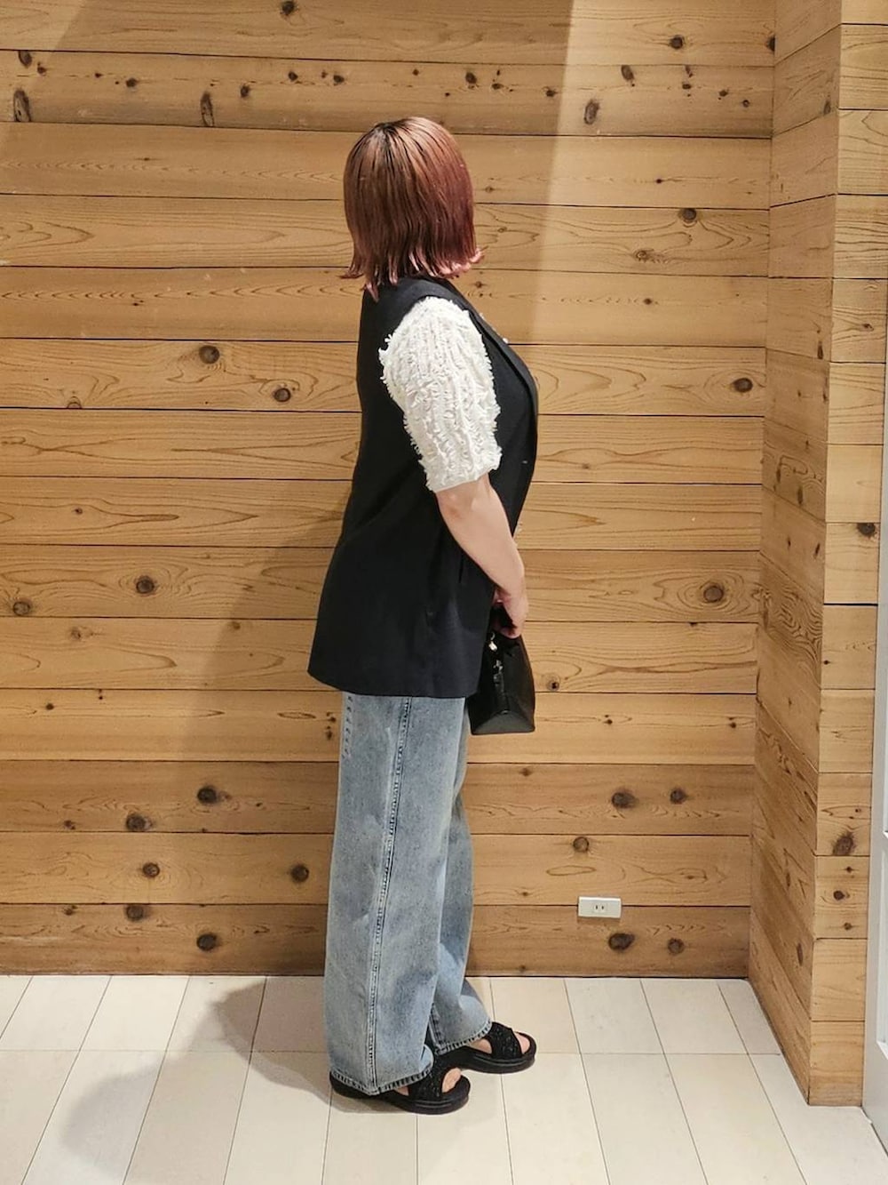 ブルー系のデニムパンツ、ブラック系のショルダーバッグ、ホワイト系のTシャツ/カットソーを着用したレディースの夏コーディネートの2枚目の写真