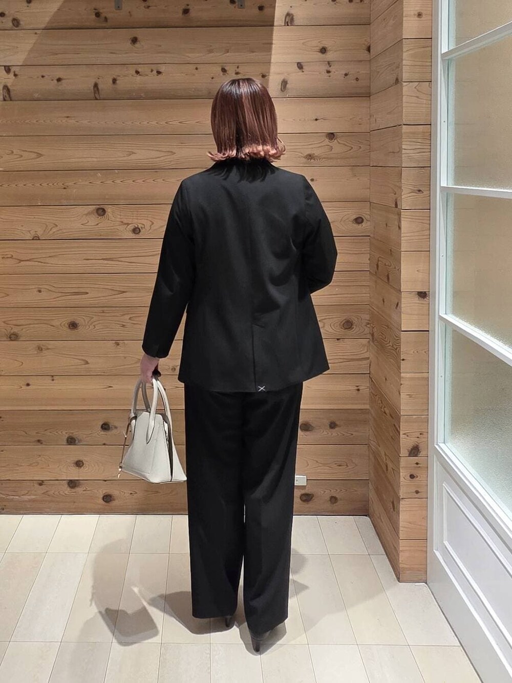 ホワイト系のショルダーバッグ、ブラック系のパンプス、ブラック系のスラックスを着用したレディースの春コーディネートの3枚目の写真