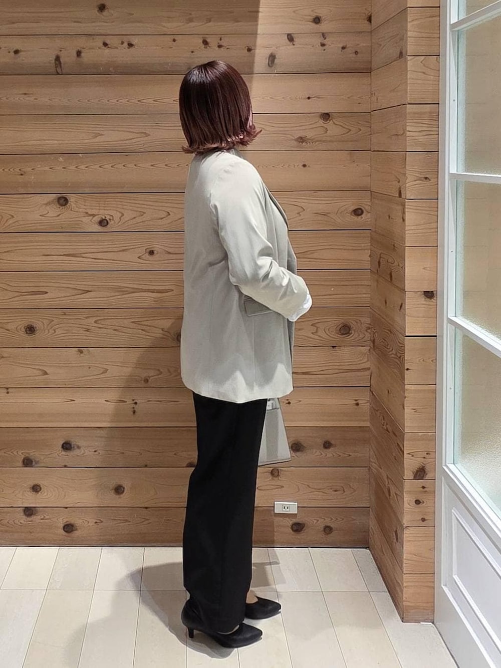 ホワイト系のショルダーバッグ、ブラック系のパンプス、ベージュ系のテーラードジャケットを着用したレディースの冬コーディネートの2枚目の写真