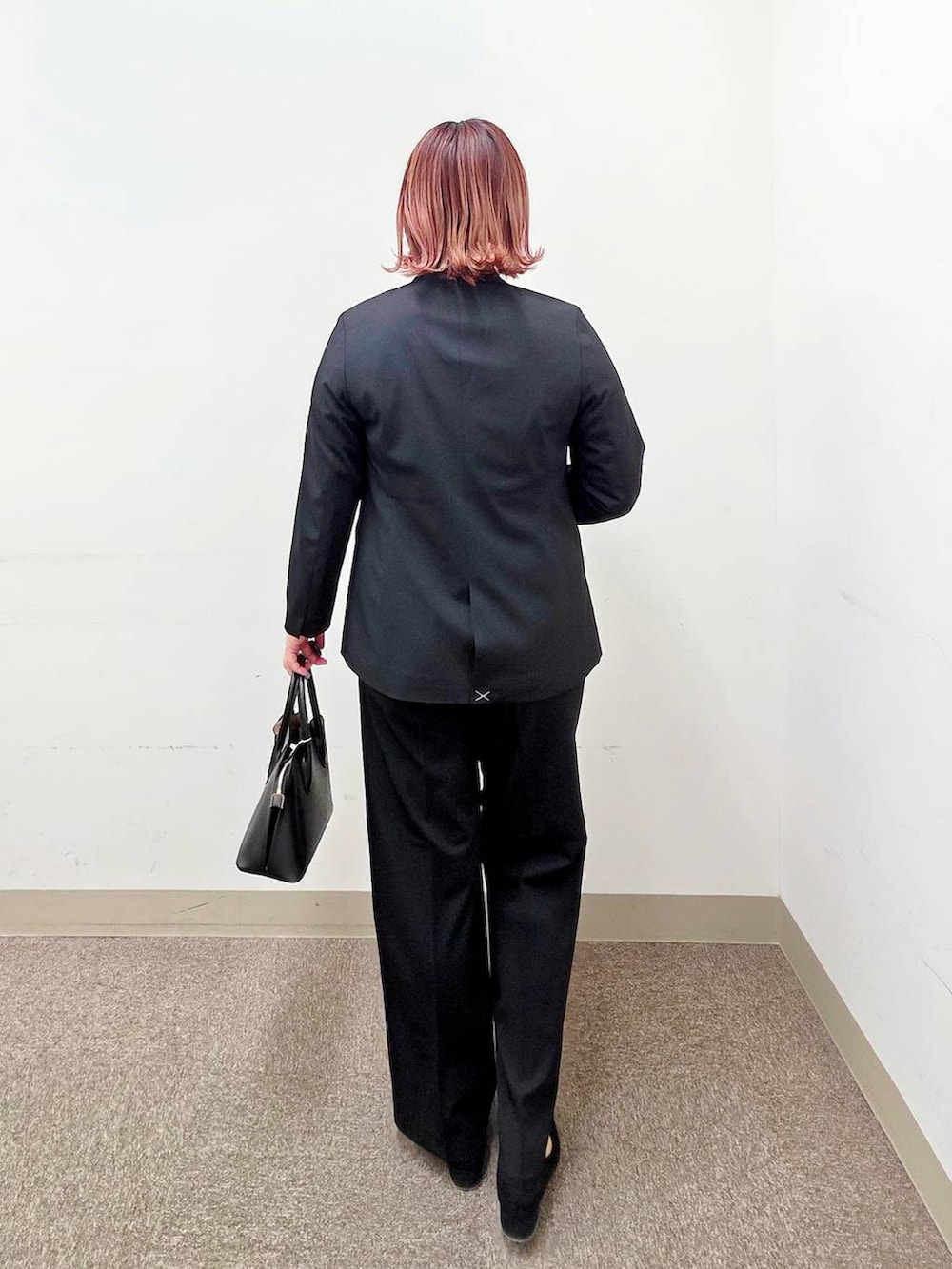 ブラック系のショルダーバッグ、ブラック系のパンプス、ブルー系のスラックスを着用したレディースの冬コーディネートの3枚目の写真