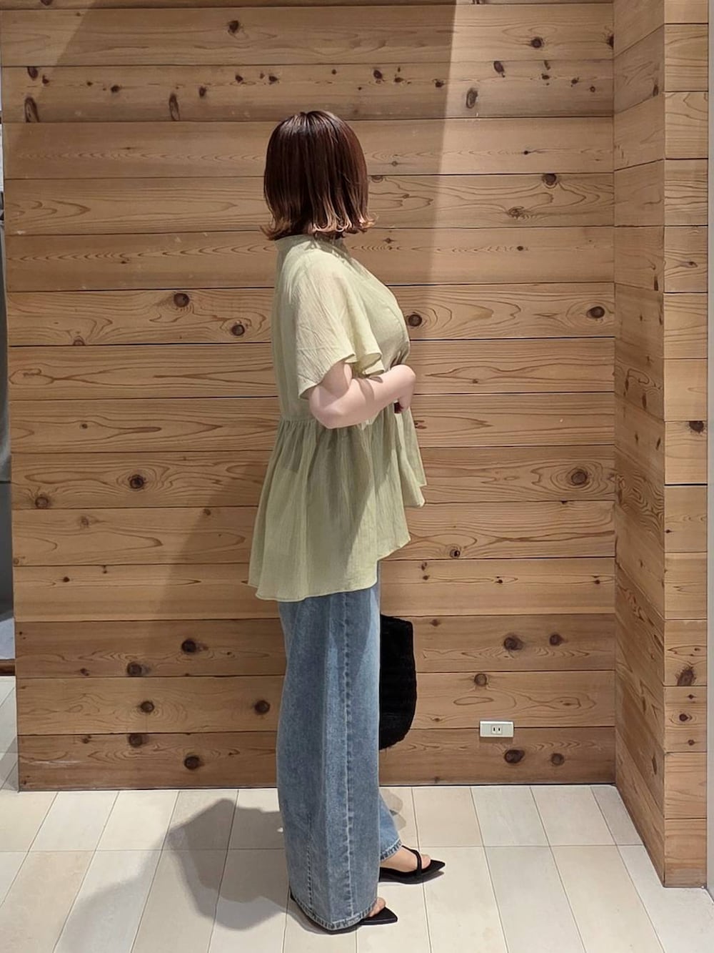 ブルー系のデニムパンツ、ホワイト系のタンクトップ、ブラック系のクラッチバッグを着用したレディースの夏コーディネートの2枚目の写真