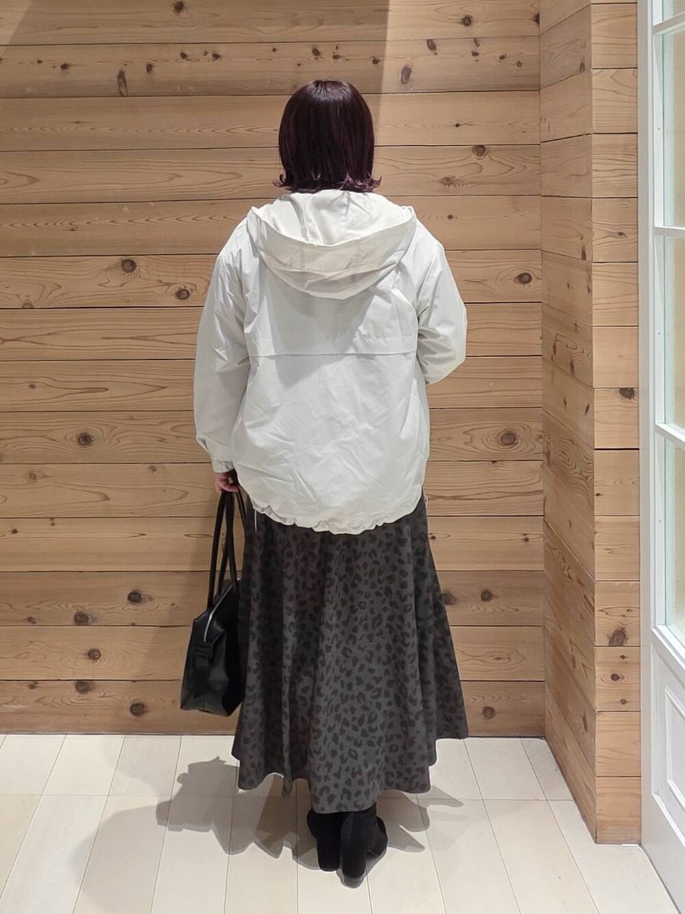 ホワイト系のマウンテンパーカー、ベージュ系のニット/セーター、ブラック系のボストンバッグを着用したレディースの冬コーディネートの3枚目の写真