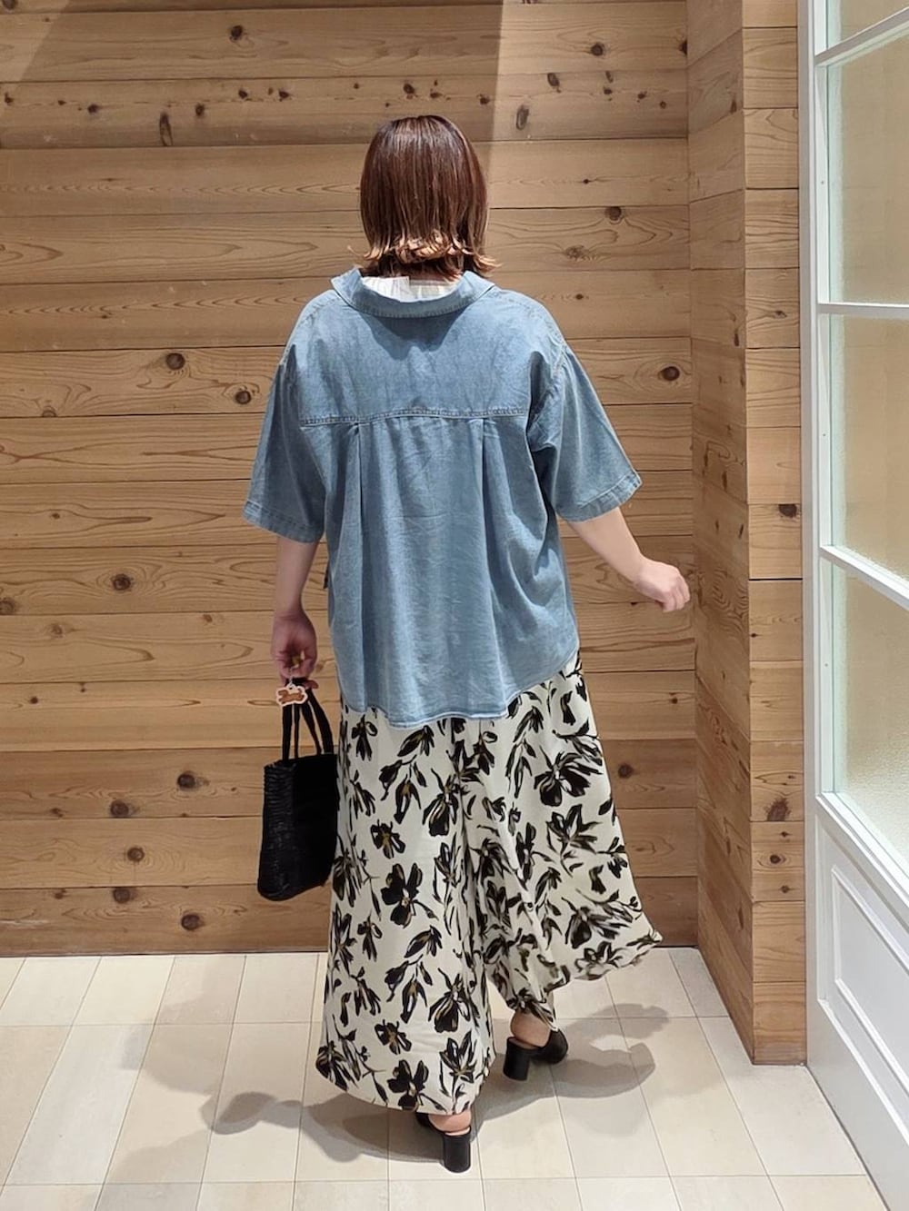 ブラック系のクラッチバッグ、ブルー系のシャツ/ブラウス、ブラック系のサンダルを着用したレディースの夏コーディネートの3枚目の写真
