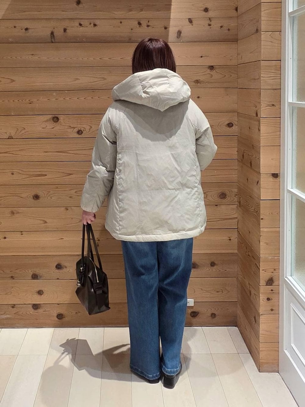 ベージュ系のダウンジャケット/コート、ブラウン系のボストンバッグ、ホワイト系のTシャツ/カットソーを着用したレディースの冬コーディネートの3枚目の写真