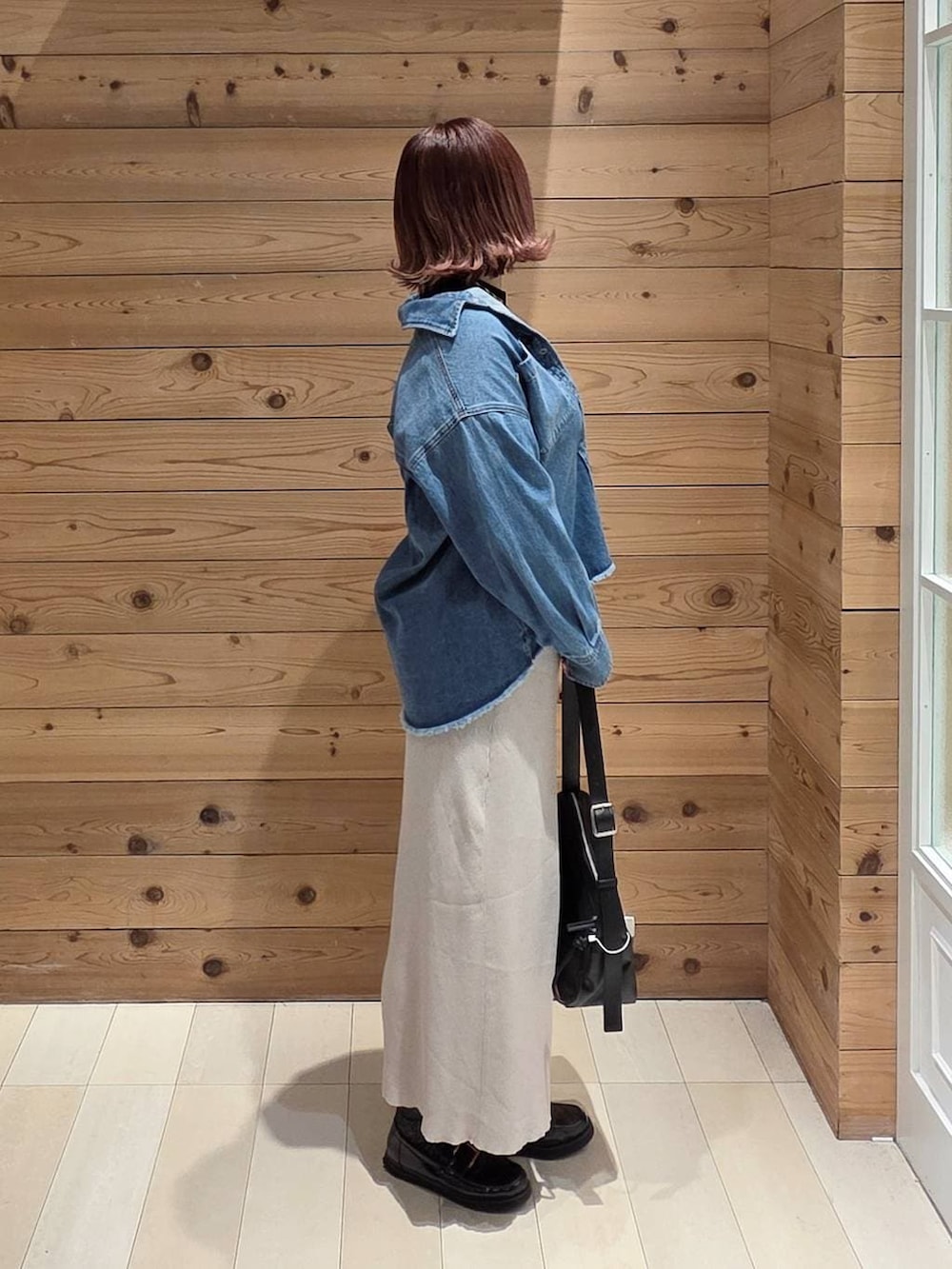 ブラック系のローファー、ブラック系のニット/セーター、ブルー系のシャツ/ブラウスを着用したレディースの春コーディネートの2枚目の写真