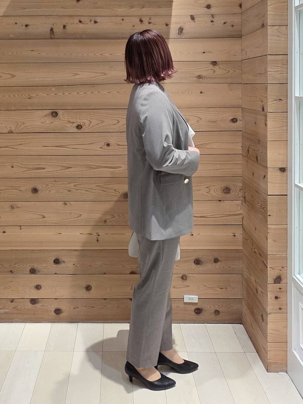 ホワイト系のショルダーバッグ、ブラック系のパンプス、ブラウン系のスラックスを着用したレディースの冬コーディネートの2枚目の写真