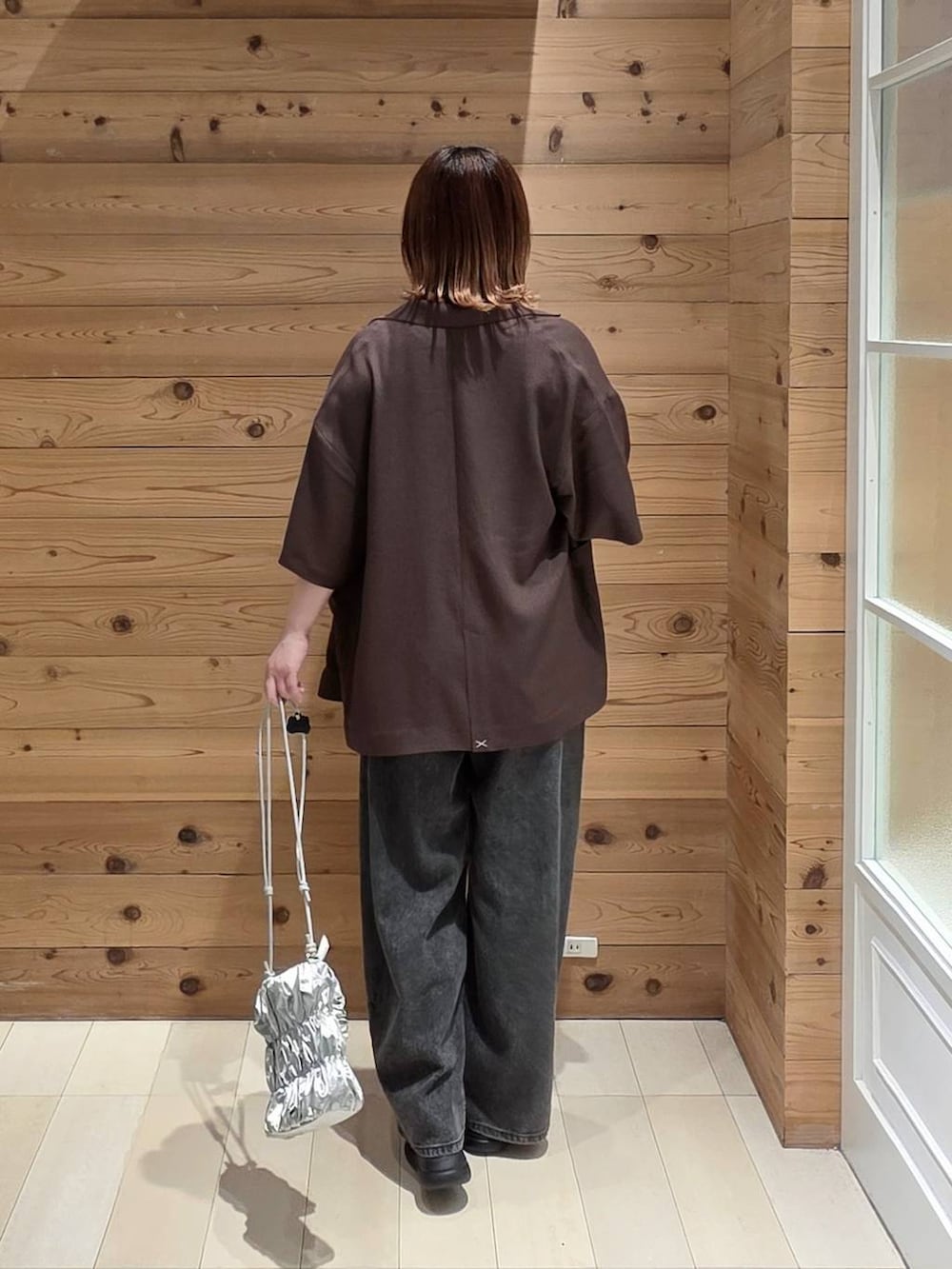 ブラック系のデニムパンツ、ブラウン系のテーラードジャケット、ブラック系のタンクトップを着用したレディースの夏コーディネートの3枚目の写真