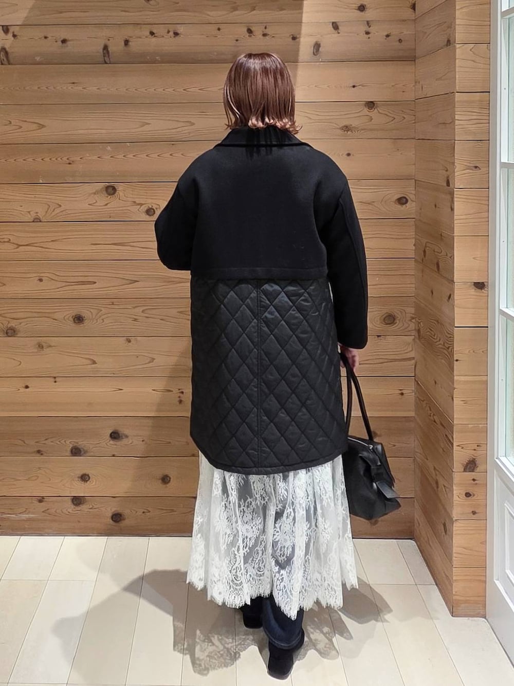 ブラック系のボストンバッグ、ブルー系のデニムパンツ、ブラック系のステンカラーコートを着用したレディースの秋コーディネートの3枚目の写真