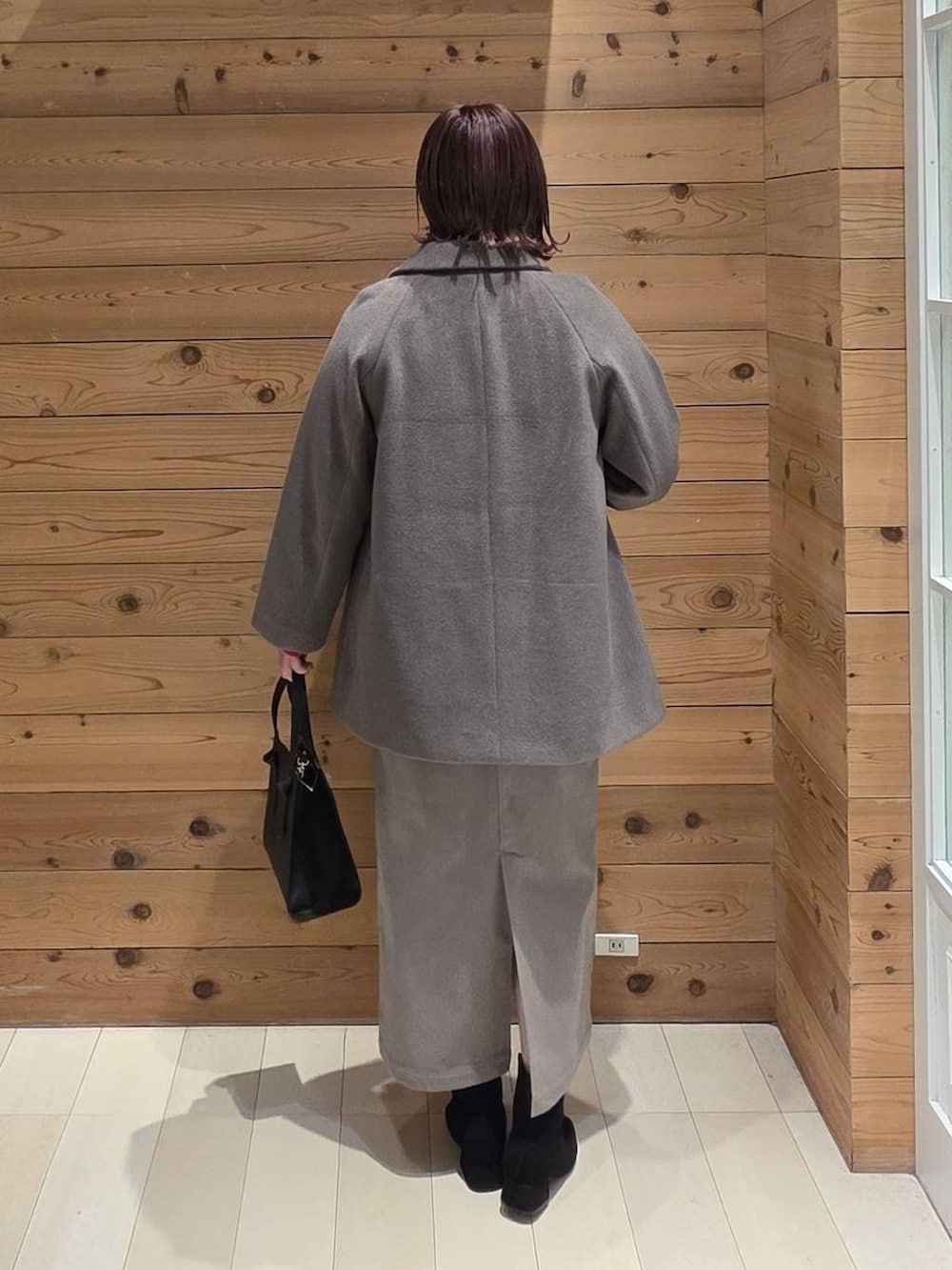 ブラック系のショルダーバッグ、ブラウン系のチェスターコート、ブラウン系のスカートを着用したレディースの冬コーディネートの3枚目の写真