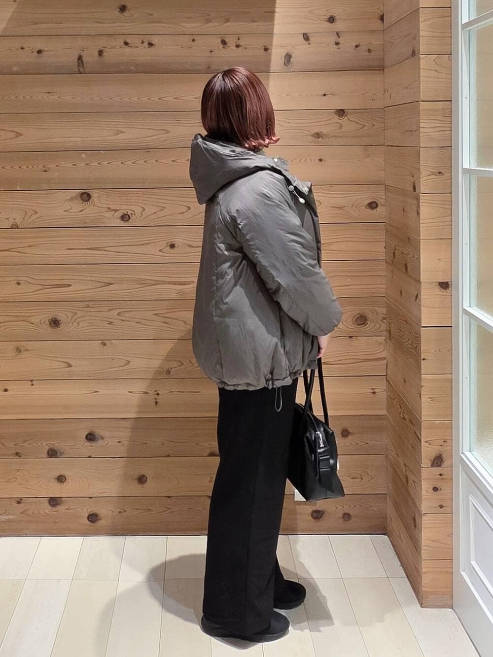 ブラウン系のダウンジャケット/コート、ブラック系のボストンバッグ、グリーン系のニット/セーターを着用したレディースの冬コーディネートの2枚目の写真