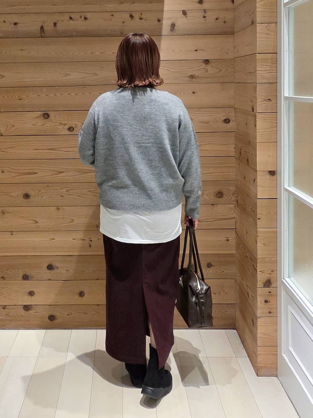 ブラウン系のボストンバッグ、ブラウン系のチェスターコート、レッド系のスカートを着用したレディースの冬コーディネートの3枚目の写真