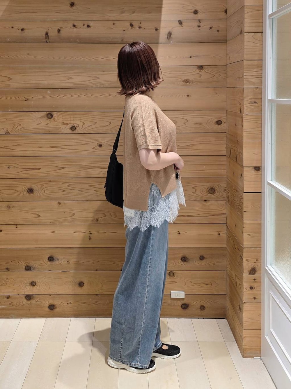 ブラック系のスニーカー、ブルー系のデニムパンツ、ブラック系のショルダーバッグを着用したレディースの春コーディネートの2枚目の写真
