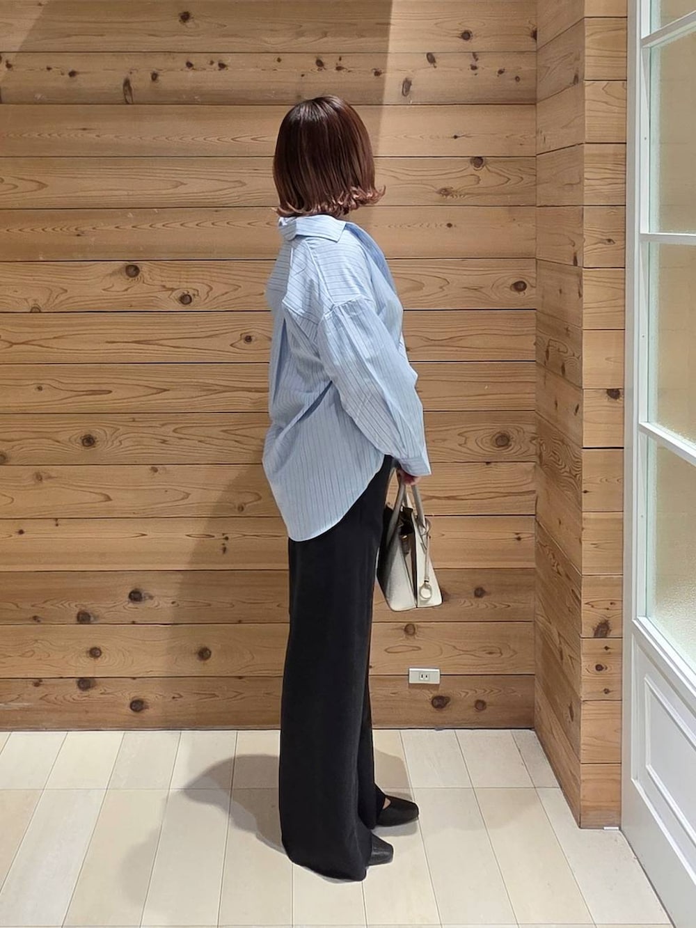 ブラック系のパンプス、ホワイト系のショルダーバッグ、ブルー系のシャツ/ブラウスを着用したレディースの春コーディネートの2枚目の写真