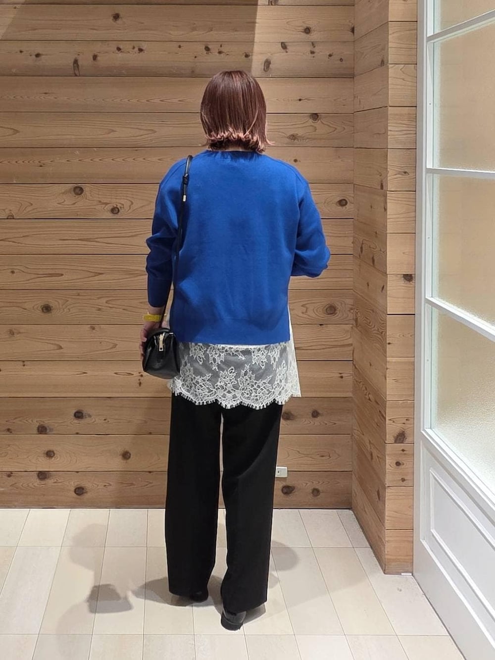 ブラック系のローファー、ブラック系のショルダーバッグ、ブラック系のスラックスを着用したレディースの春コーディネートの3枚目の写真