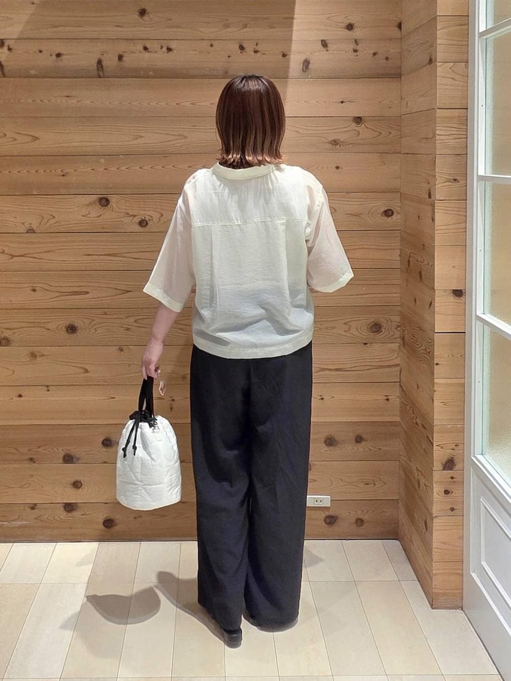 ホワイト系のハンドバッグ、ブラック系のその他パンツ、ホワイト系のシャツ/ブラウスを着用したレディースの夏コーディネートの3枚目の写真