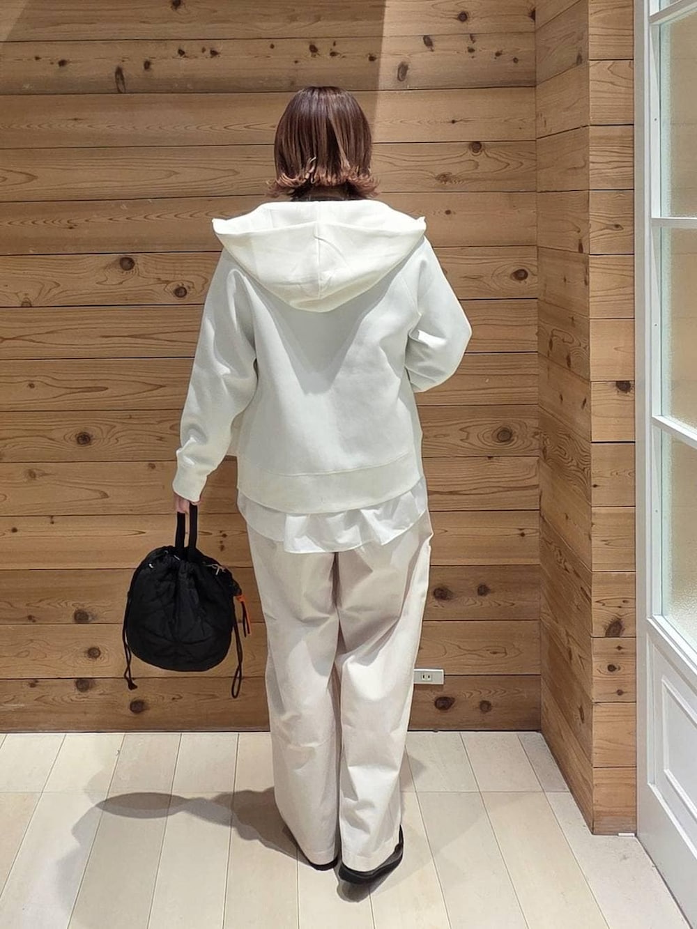 ブラック系のローファー、ブラック系のハンドバッグ、ホワイト系のパーカーを着用したレディースの春コーディネートの3枚目の写真