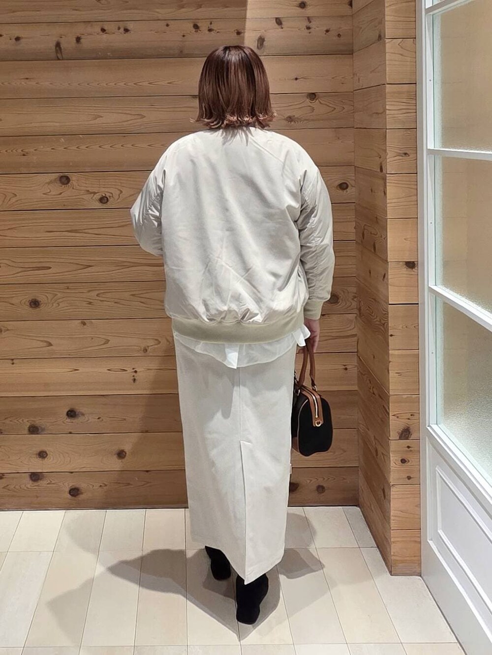 グレー系のニット/セーター、ベージュ系のブルゾン、グレー系のスカートを着用したレディースの冬コーディネートの3枚目の写真