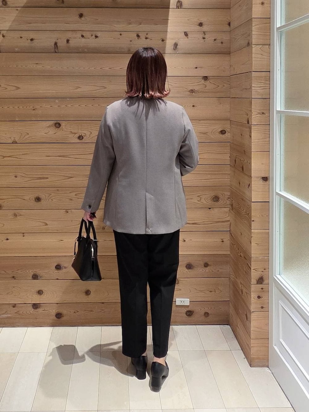 ブラック系のローファー、ブラック系のショルダーバッグ、ブラック系のスラックスを着用したレディースの冬コーディネートの3枚目の写真