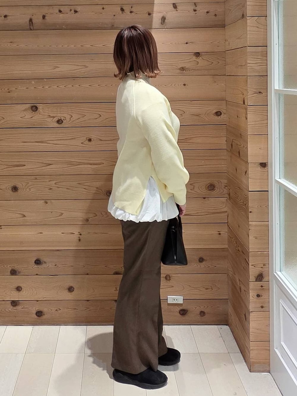 ブラック系のショルダーバッグ、ベージュ系のダウンジャケット/コート、ブラック系のブーツを着用したレディースの冬コーディネートの2枚目の写真