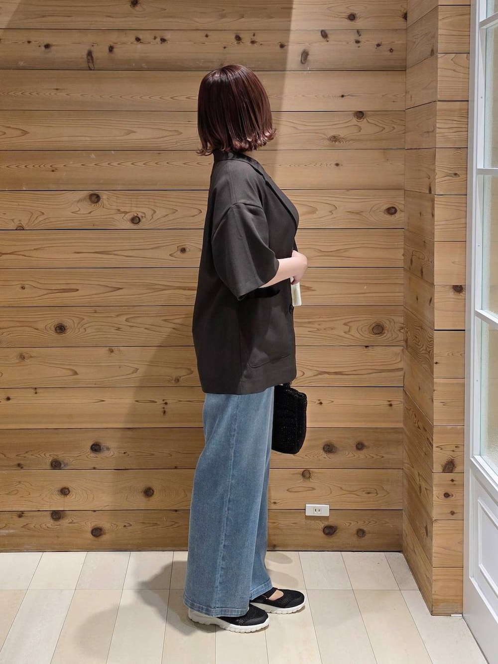 ブラック系のスニーカー、ブルー系のデニムパンツ、ブラック系のタンクトップを着用したレディースの春コーディネートの2枚目の写真