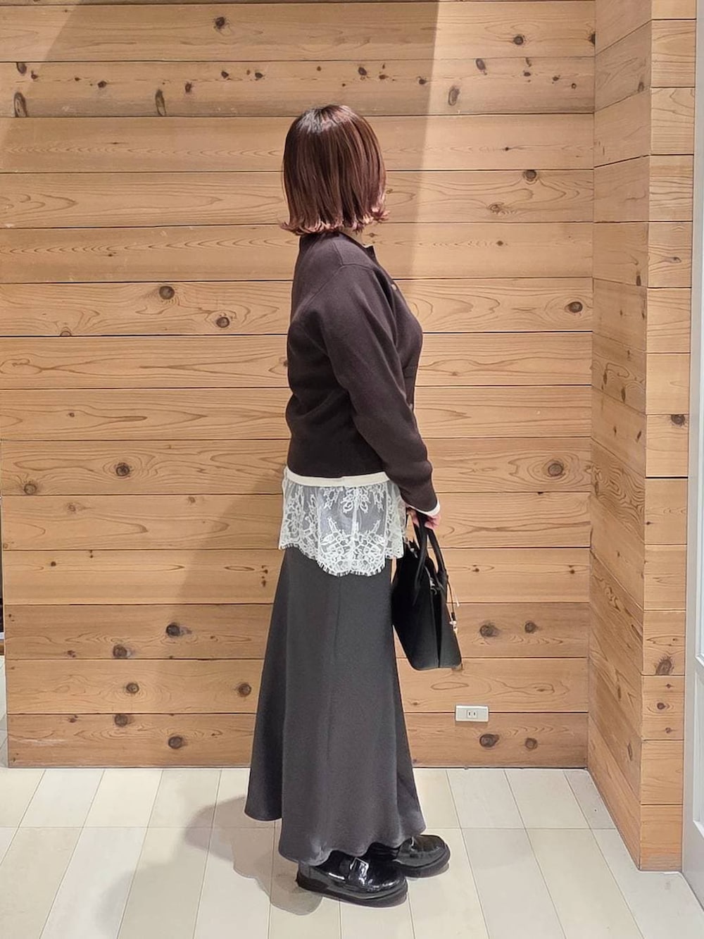 ブラック系のローファー、ブラック系のショルダーバッグ、グレー系のスカートを着用したレディースの冬コーディネートの2枚目の写真