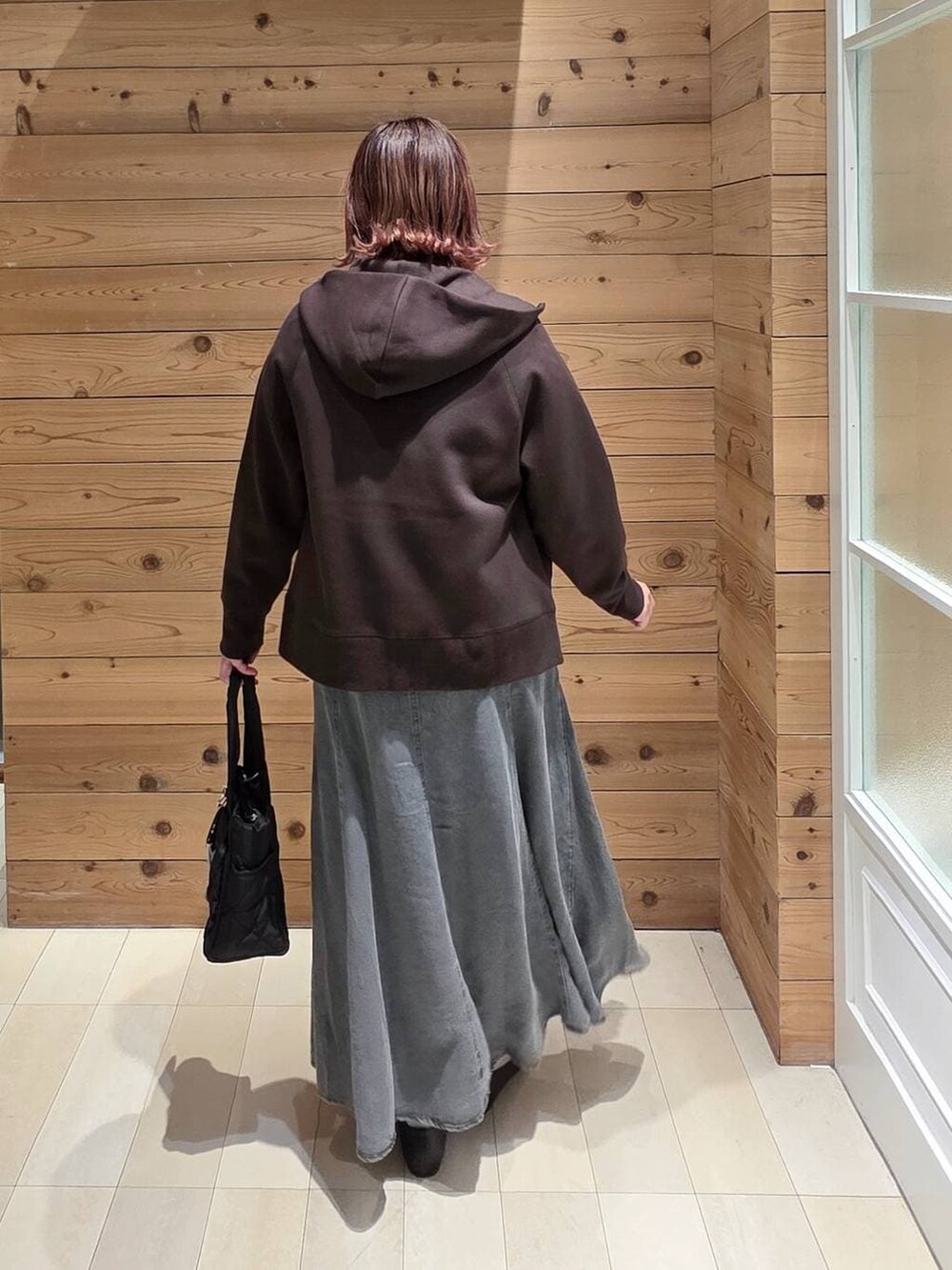 ブラック系のパンプス、ブラック系のトートバッグ、ブラウン系のパーカーを着用したレディースの冬コーディネートの3枚目の写真