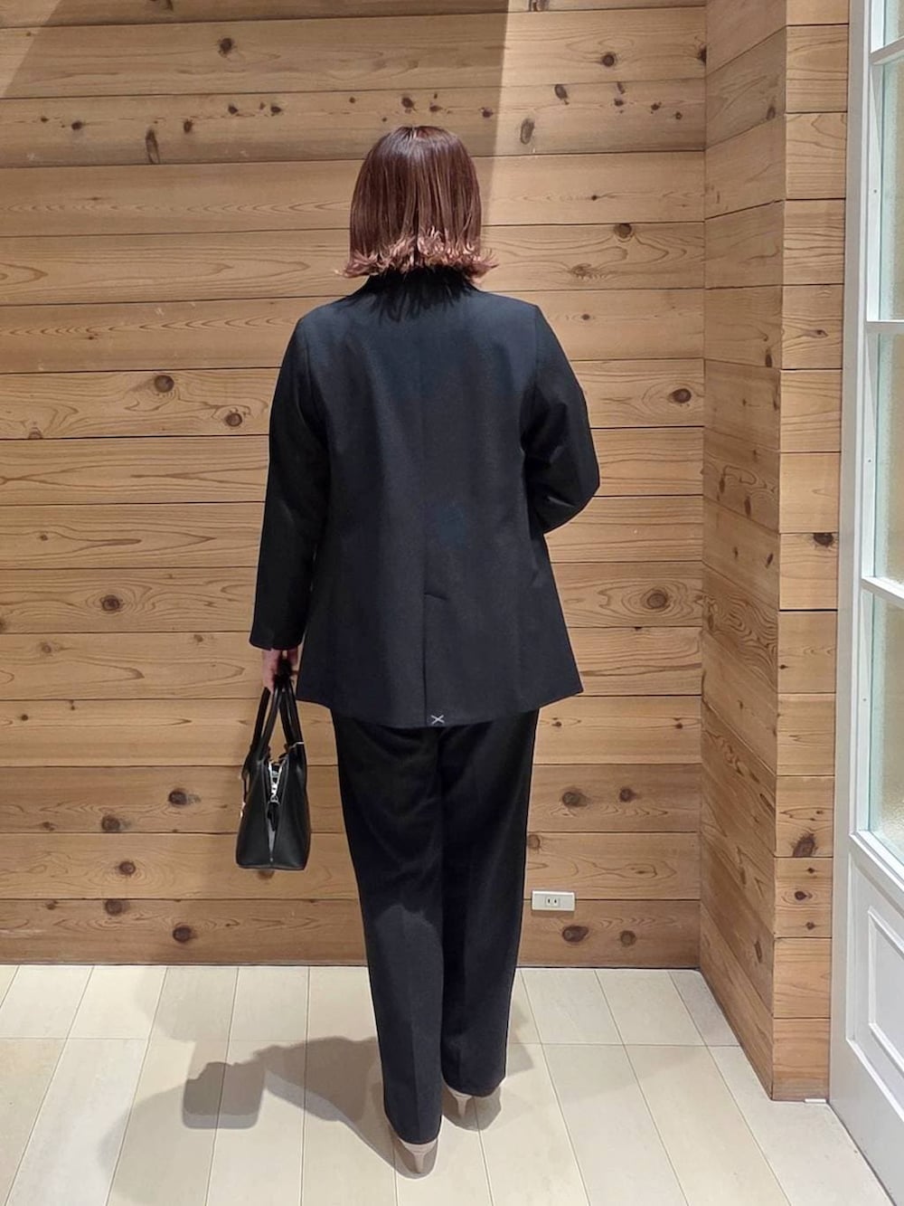 ブラック系のショルダーバッグ、ホワイト系のパンプス、ブルー系のスラックスを着用したレディースの春コーディネートの3枚目の写真