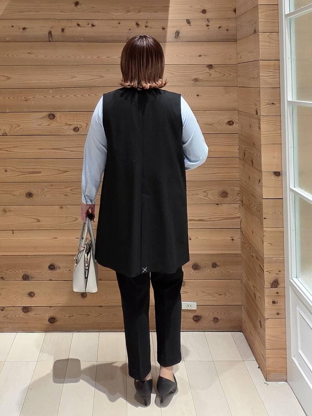 ホワイト系のショルダーバッグ、ブラック系のパンプス、ブラック系のスラックスを着用したレディースの冬コーディネートの3枚目の写真