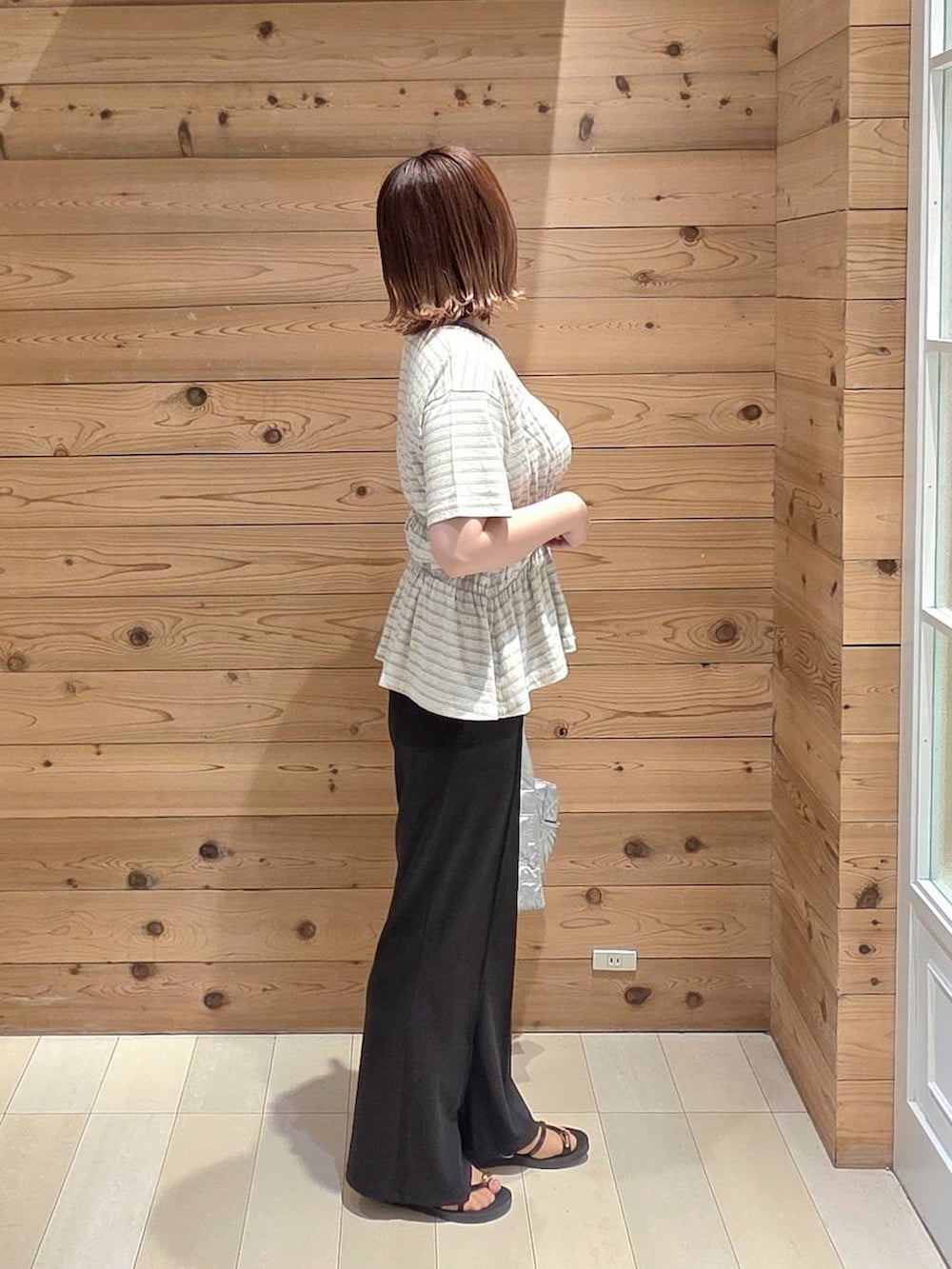 シルバー系のトートバッグ、ブラック系のサンダル、ホワイト系のTシャツ/カットソーを着用したレディースの夏コーディネートの2枚目の写真